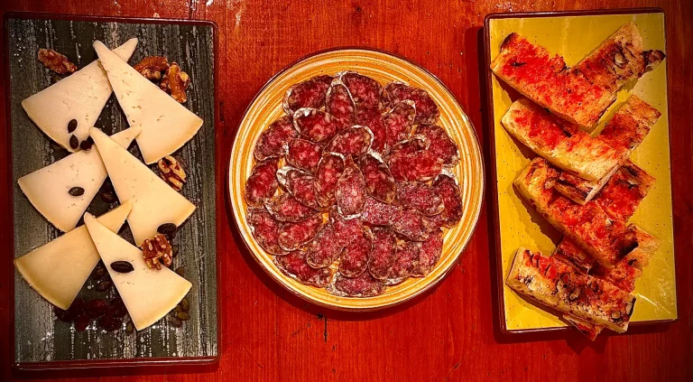 Plato de salchichón ibérico entre cuñas de queso manchego y pan con tomate