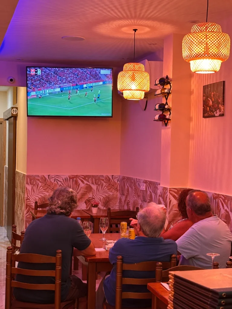 Clientes viendo un partido de fútbol en la pantalla del comedor